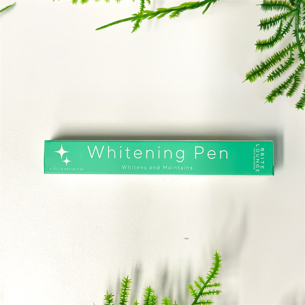 The Brite Lounge Whitening Pen box, photographed with greenery